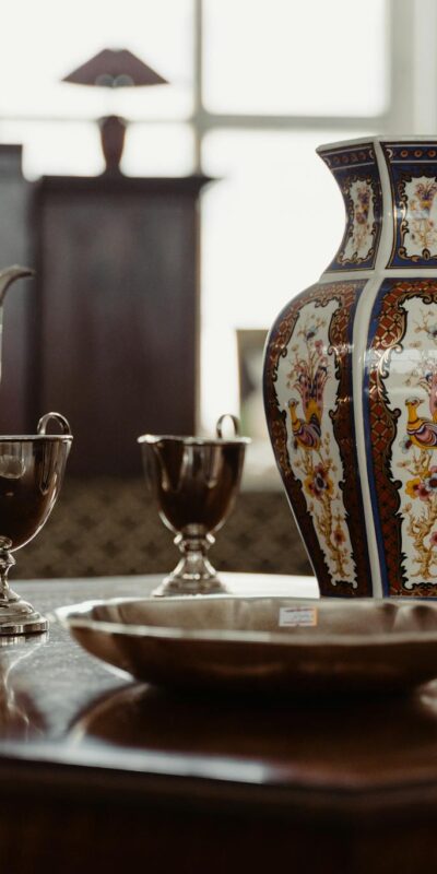 A collection of antique metalware and ceramics on a wooden table, capturing a vintage aesthetic.