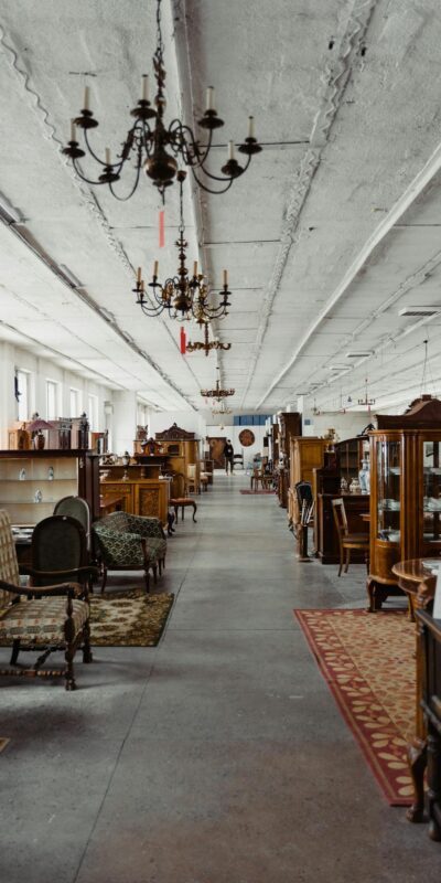 A long aisle in a vintage furniture store showcasing antique wooden pieces and chandeliers.