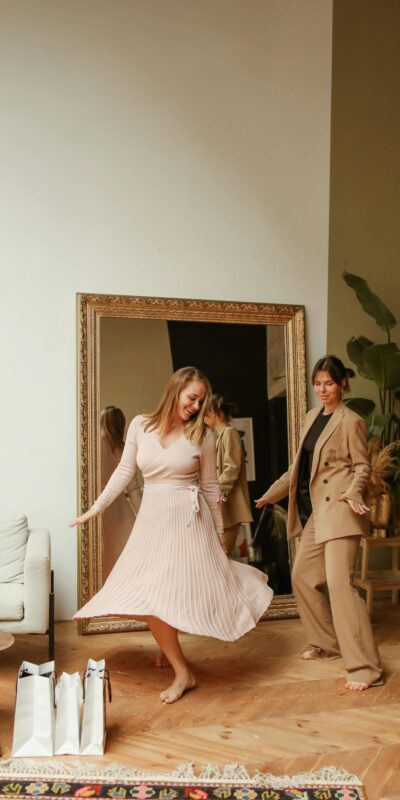 Two women having fun at home after a shopping spree, surrounded by plants and decor.